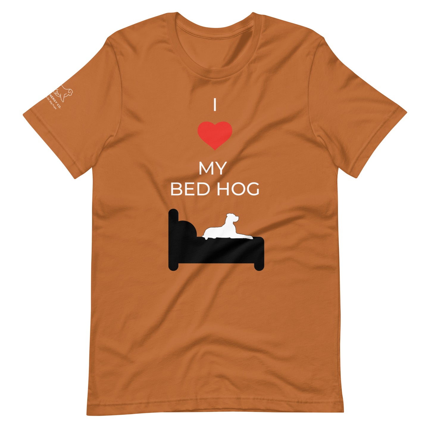 Front of a toast orange t-shirt that reads "I love my bed hog" in white text over an illustration that is the white silhouette of a large dog laying on the dark silhouette of a bed. The word "love" is replaced by a red heart symbol.