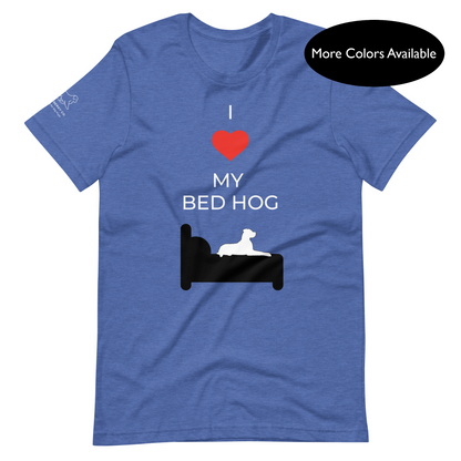 Front of a heather royal blue t-shirt that reads "I love my bed hog" in white text over an illustration that is the white silhouette of a large dog laying on the black silhouette of a bed. The word "love" is represented by a red heart.