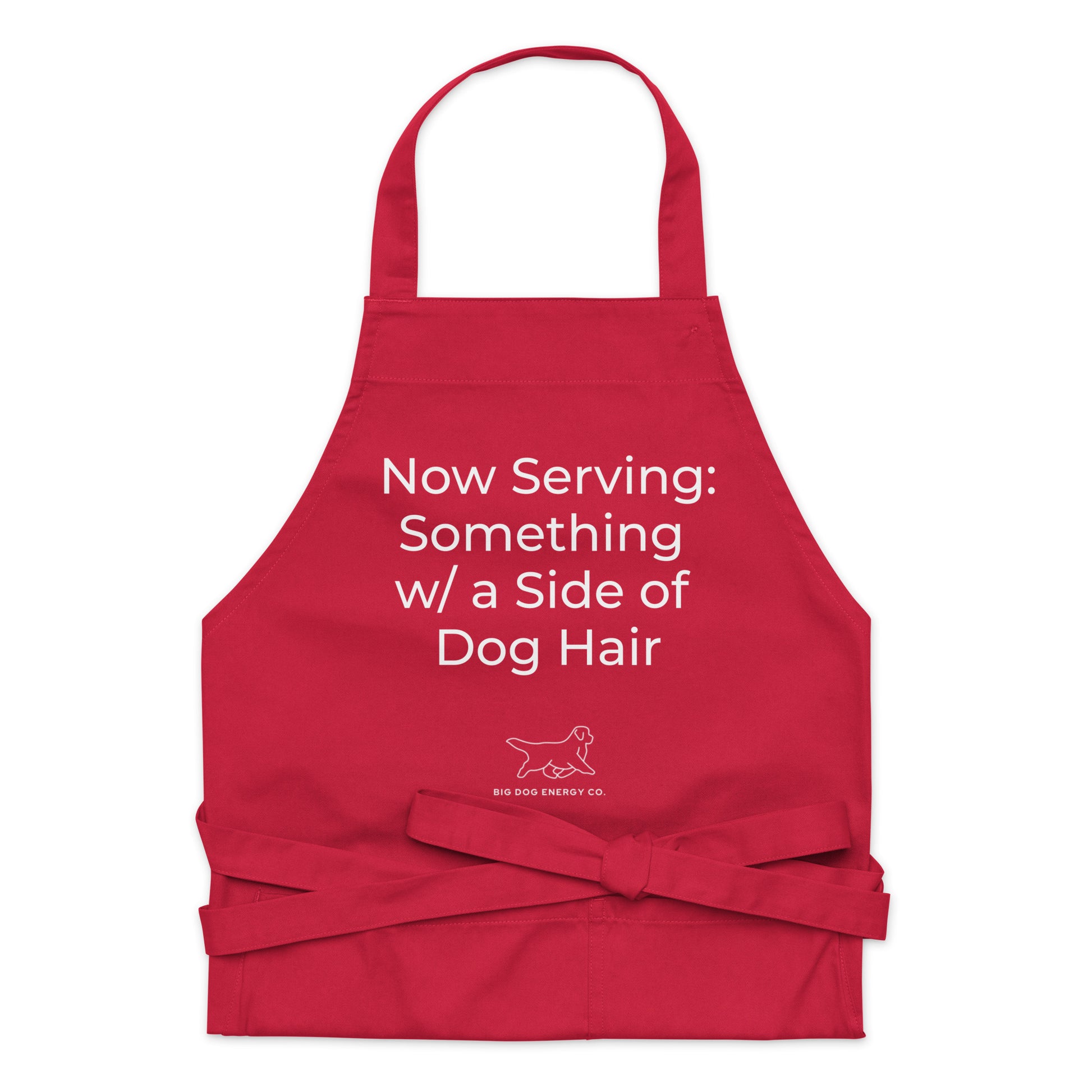 Red cooking apron with the saying "Now Serving: Something with a side of dog hair" in white text over a white Big Dog Energy Company logo