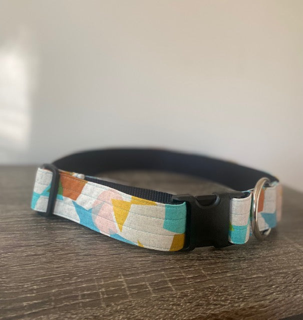 Side view of large dog collar with brightly colored geometric shapes, black plastic buckle, and large gauge D ring.