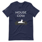 Front of a navy blue t-shirt that reads "House Cow" in white text over an illustration that is the white silhouette of a large dog laying on the dark silhouette of a couch.