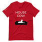 Front of a red t-shirt that reads "House Cow" in white text over an illustration that is the white silhouette of a large dog laying on the dark silhouette of a couch.