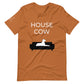 Front of a toast orange t-shirt that reads "House Cow" in white text over an illustration that is the white silhouette of a large dog laying on the dark silhouette of a couch.